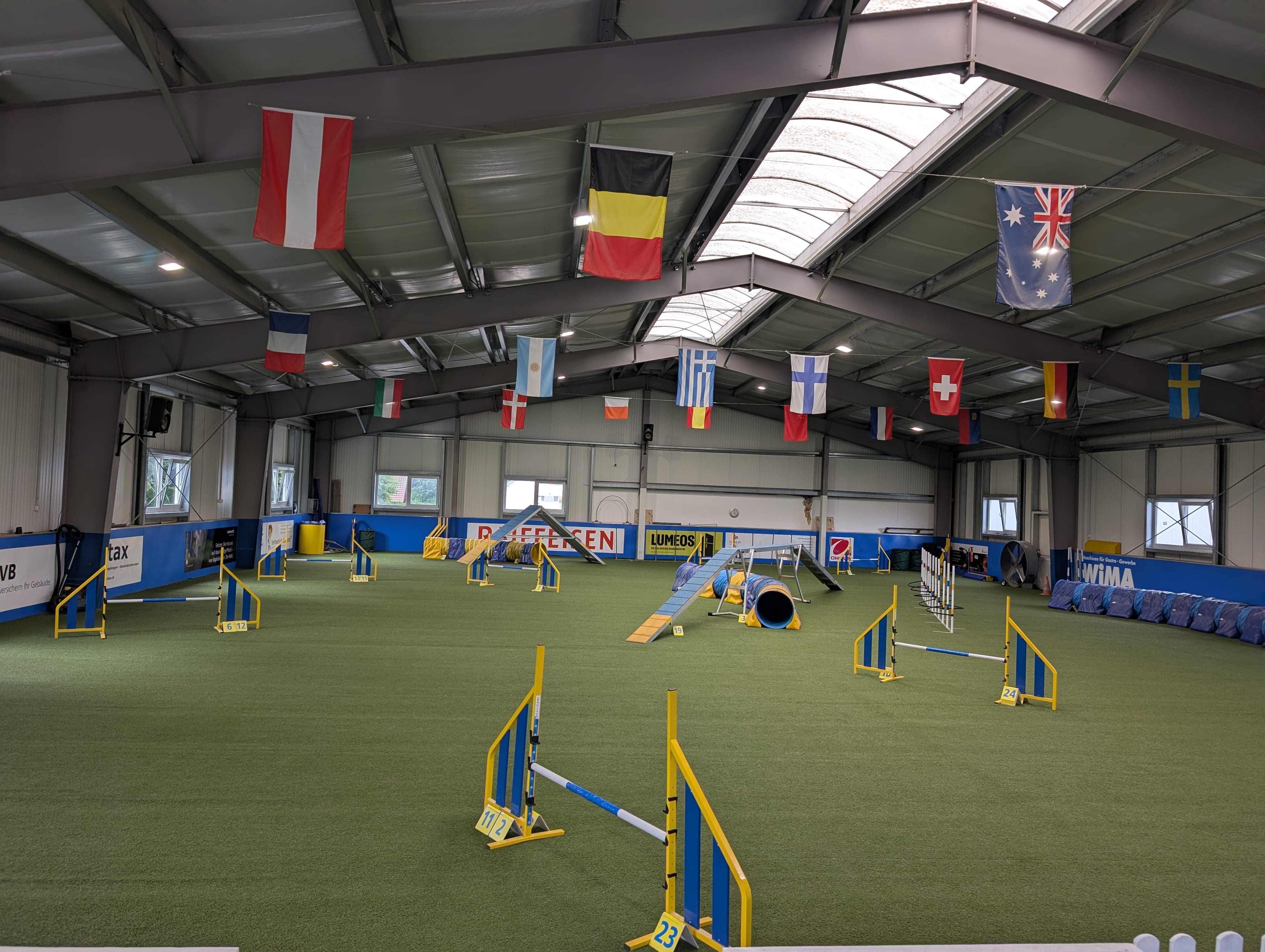 Innenansicht der Trainings-Halle in Aarwangen — kompletter Agility-Parcours mit Hürden, Slalom, Reifen, Tunnel und Kontaktzonen-Steg.